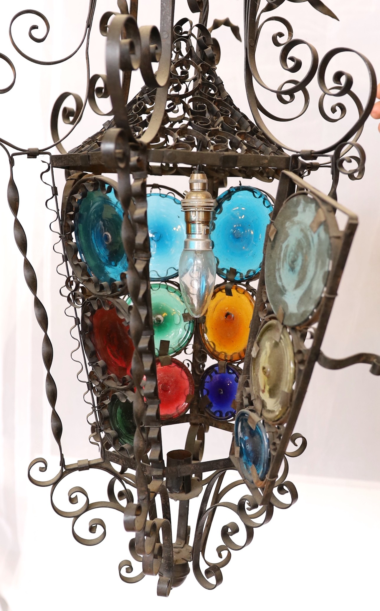 An early 20th century French wrought iron and coloured glass lantern of tapering hexagonal form, height 80cm. width 50cm